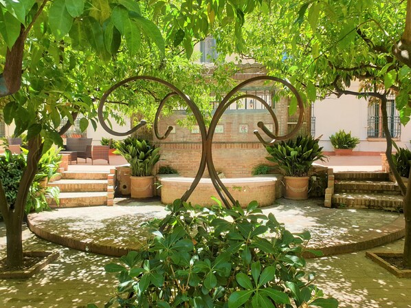 A courtyard with a central metal sculpture, potted plants, and a brick wall in the background. - OS-Garden Maison de central charm with large private garden and parking (Salerno)