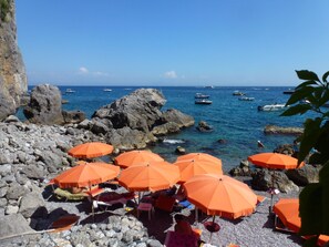 A rocky beach with orange umbrellas and people relaxing. - OS-Garden Maison de central charm with large private garden and parking (Salerno)