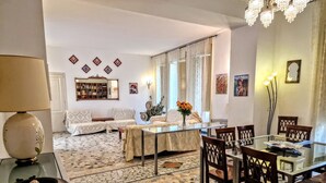 Una sala de estar con una mesa de comedor de vidrio, sofás, una mesa de centro y un suelo estampado.