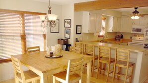 Une cuisine avec des meubles en bois, un îlot central doté de sièges et un ventilateur de plafond.