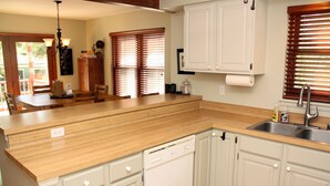 Une cuisine dotée de plans de travail en bois, de meubles blancs et d’un lave-vaisselle encastré.