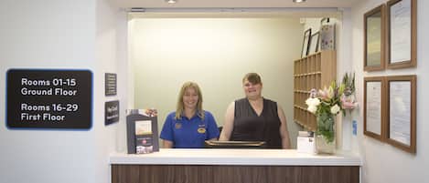 A reception desk with a 'Welcome' sign, a directory for rooms on the ground floor, and a key card holder.