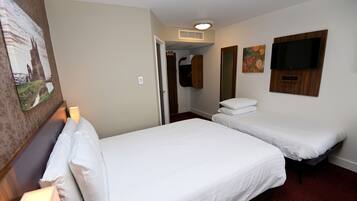A hotel room with two single beds, a TV mounted on the wall, a closet, and a painting on the wall.