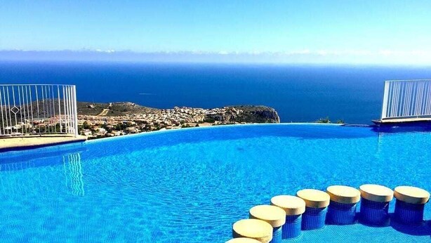 En pool med krystalklart havudsigt og en by i det fjerne.