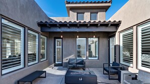 An outdoor patio with a fire pit, seating, and large windows. - Zane's Place (St. George)