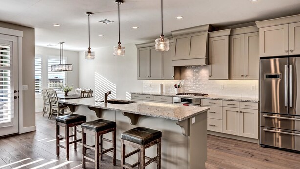 A modern kitchen with a central island, bar stools, pendant lighting, and stainless steel appliances. - Zane's Place (St. George)