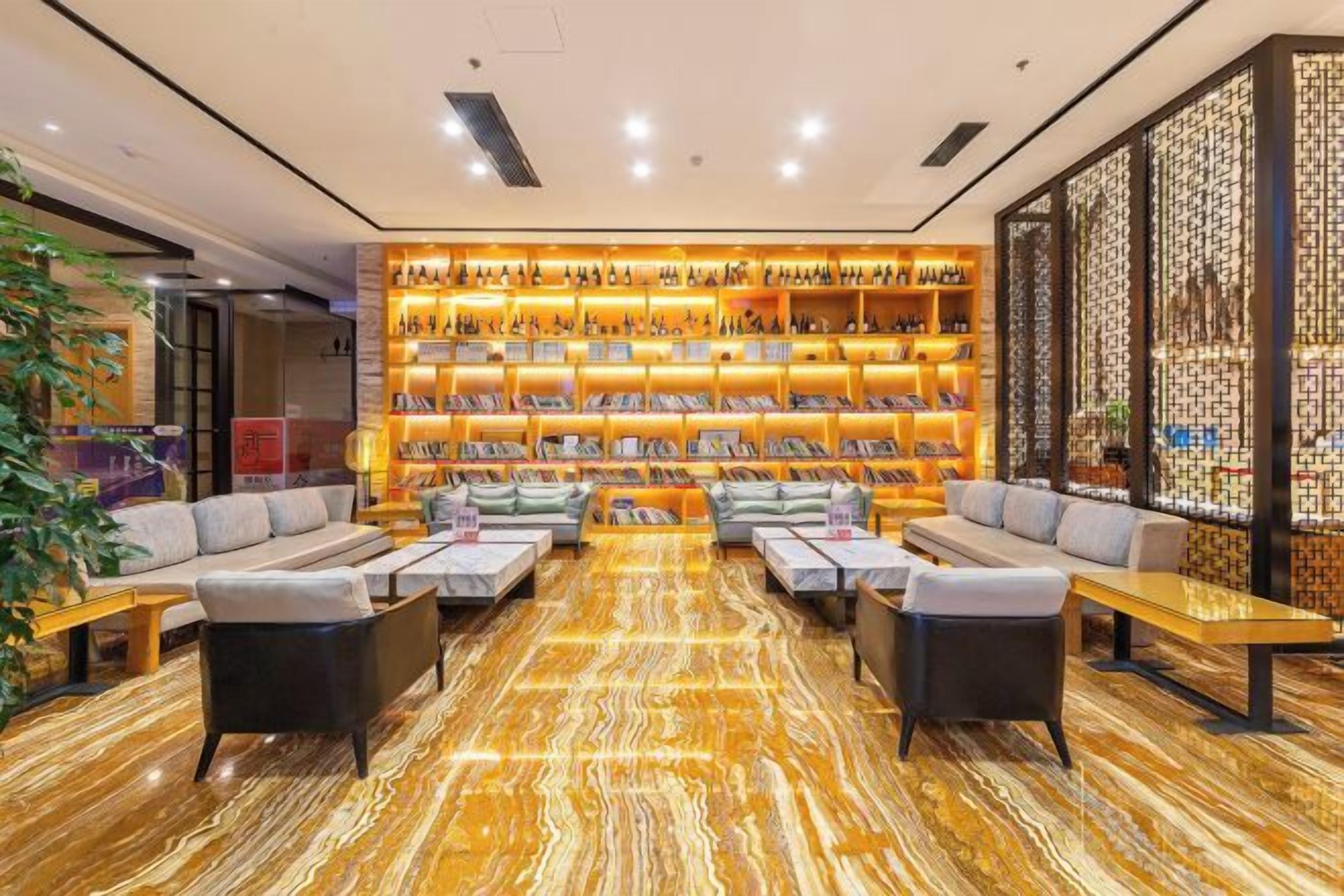 A hotel lobby with a seating area, a wall of bookshelves, and a patterned floor.