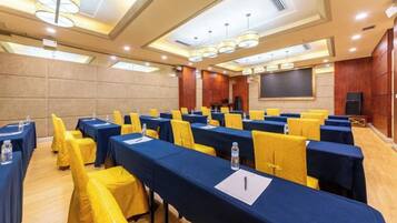 A conference room with tables and chairs, a projector screen, and a presentation area.