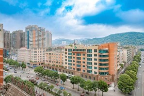 A multi-story building with a central courtyard, surrounded by trees and a busy street. - Times Holiday Hotel (Liupanshui)