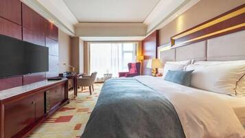 A hotel room with a large bed, a TV, a desk, and a chair.