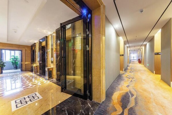 A hotel corridor with a marble floor, glass doors, and a long hallway. - Times Holiday Hotel (Liupanshui)