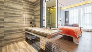 A modern hotel room with a large bed, a bathroom with a vanity, and a large mirror. - Times Holiday Hotel (Liupanshui)