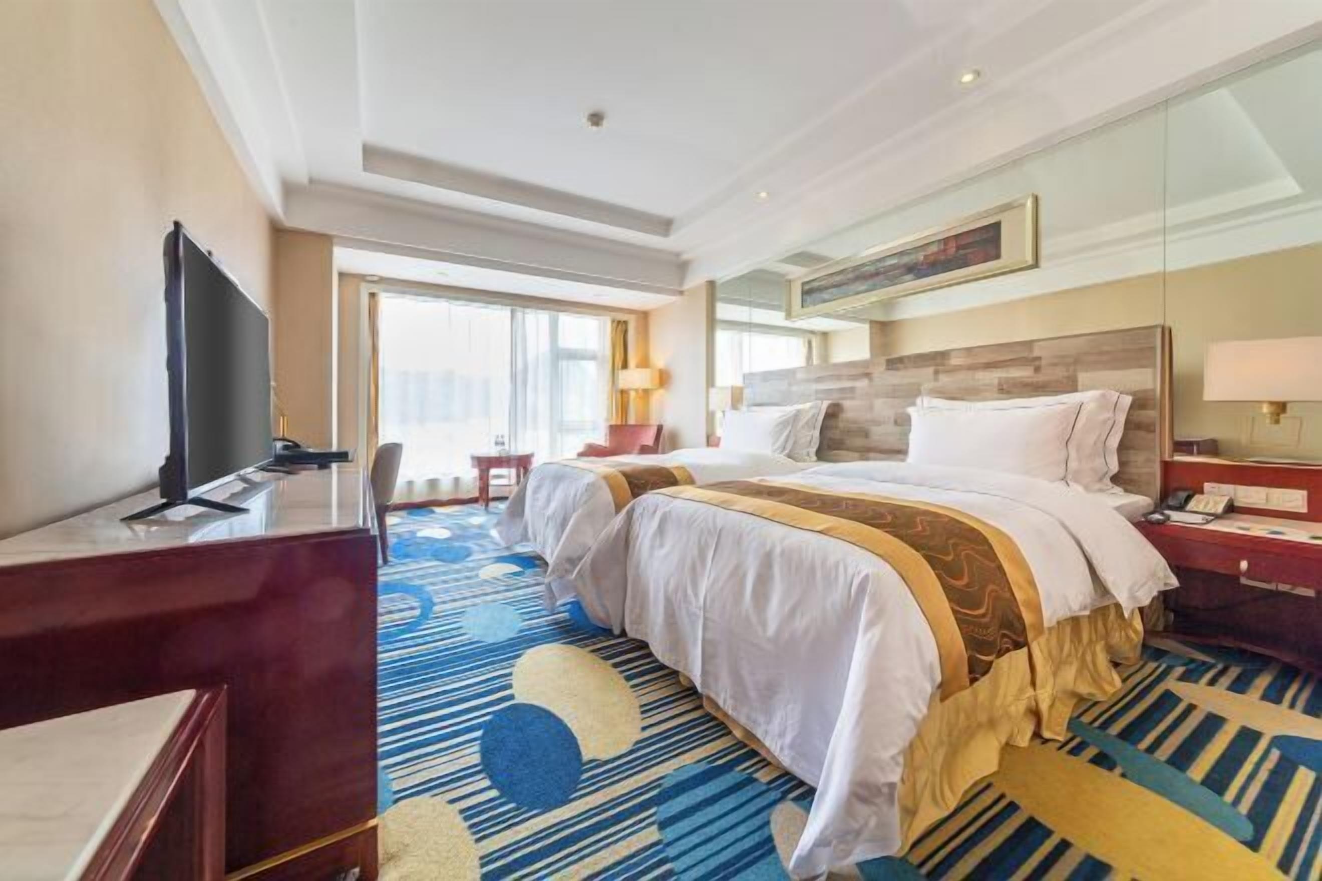 Ein Hotelzimmer mit einem großen Bett, einem Schreibtisch, einem Fernseher und einem Fenster mit Blick.