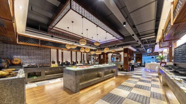 A modern restaurant interior with a central counter, wooden flooring, and hanging lanterns. - Times Holiday Hotel (Liupanshui)