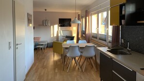 Une cuisine moderne avec un coin repas, un plancher en bois et de grandes fenêtres.