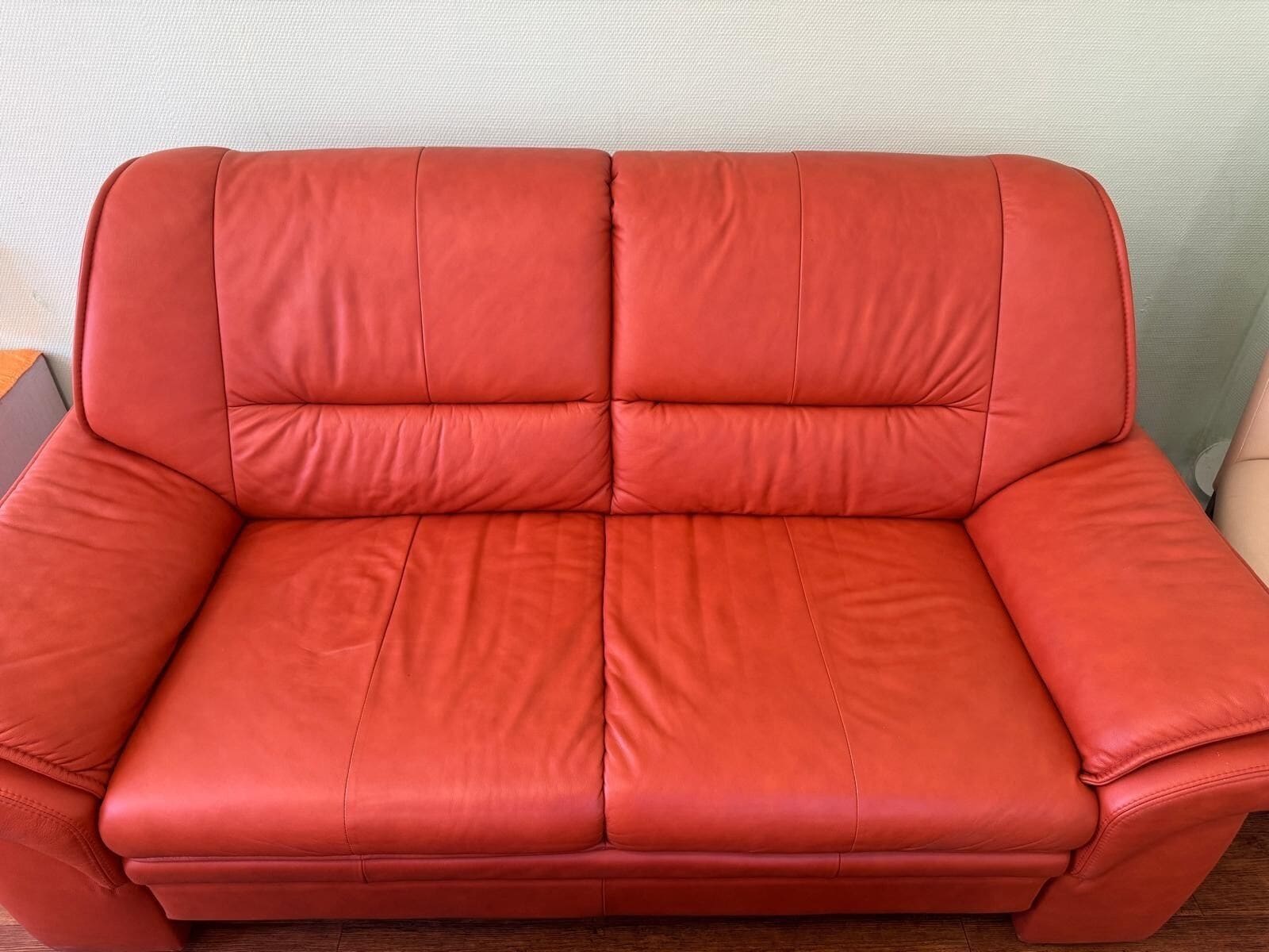 A red leather sofa with a cushioned backrest and armrests.