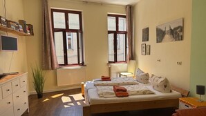 A bedroom with a bed, a desk, a chair, a radiator, and two windows. - Gästehaus Innfernow (Fürstenberg-Havel)