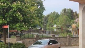 A car parked in a driveway with a chain barrier, a sign indicating a path to a lake, and a bridge in the background. - Gästehaus Innfernow (Fürstenberg-Havel)
