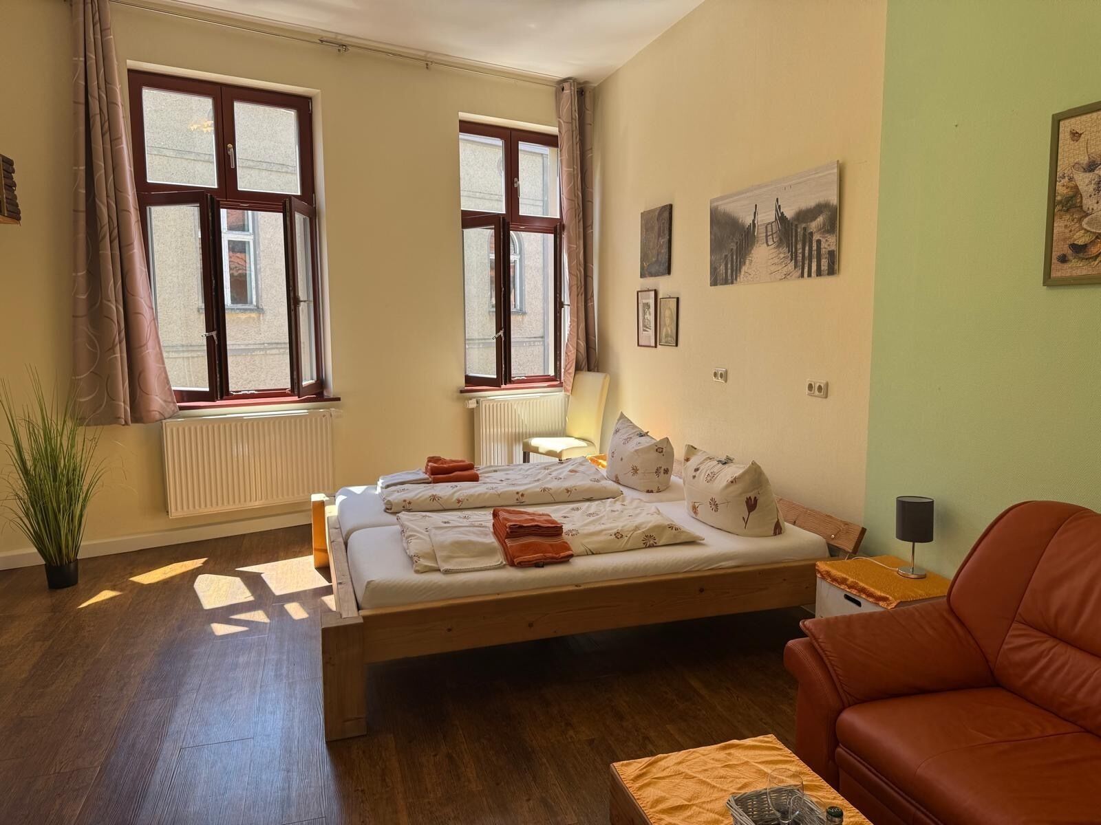 A bedroom with a bed, a chair, a radiator, and a window.