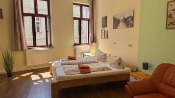A bedroom with a bed, a chair, a radiator, and a window.