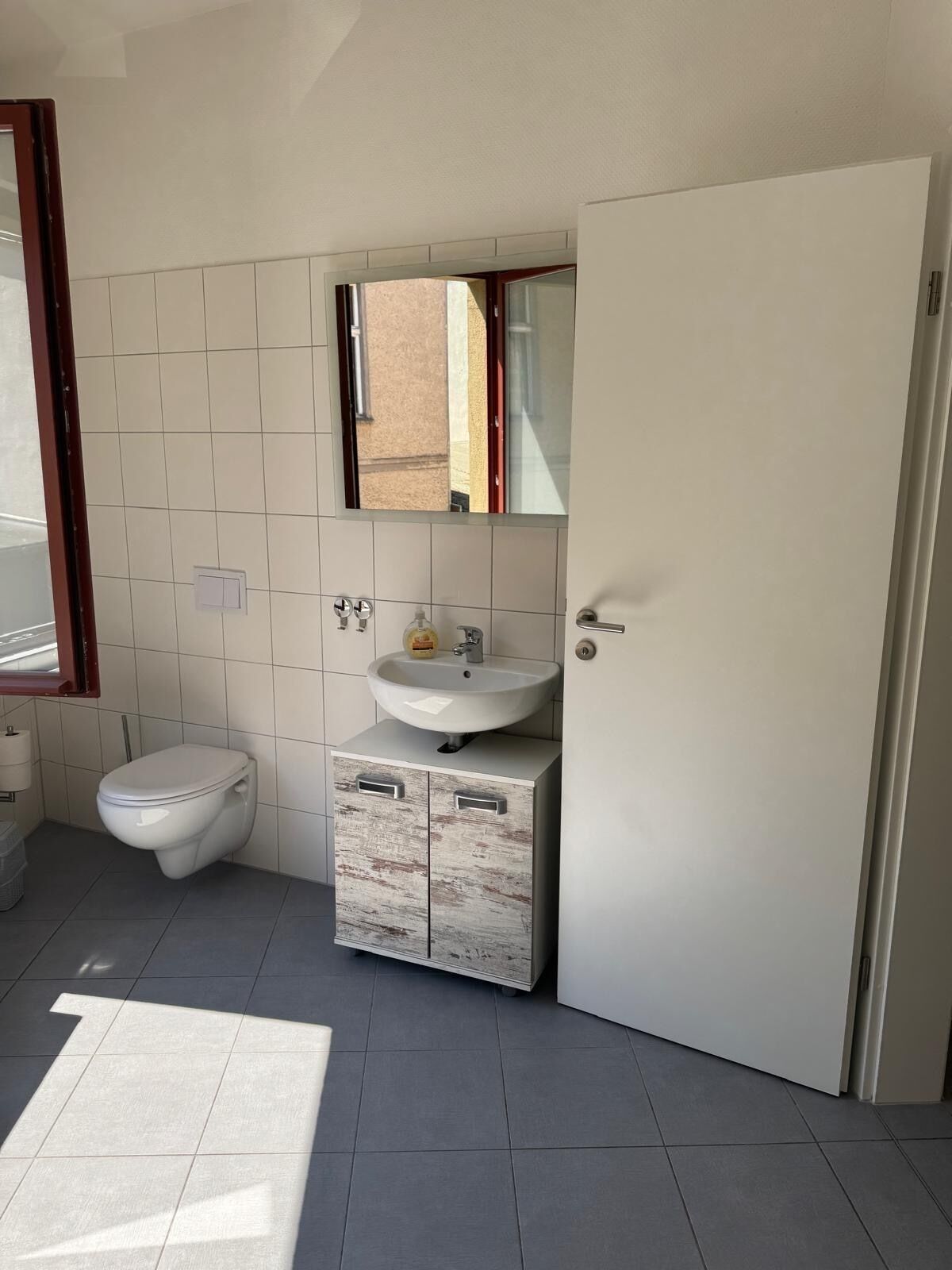 A bathroom with a toilet, sink, and mirror.