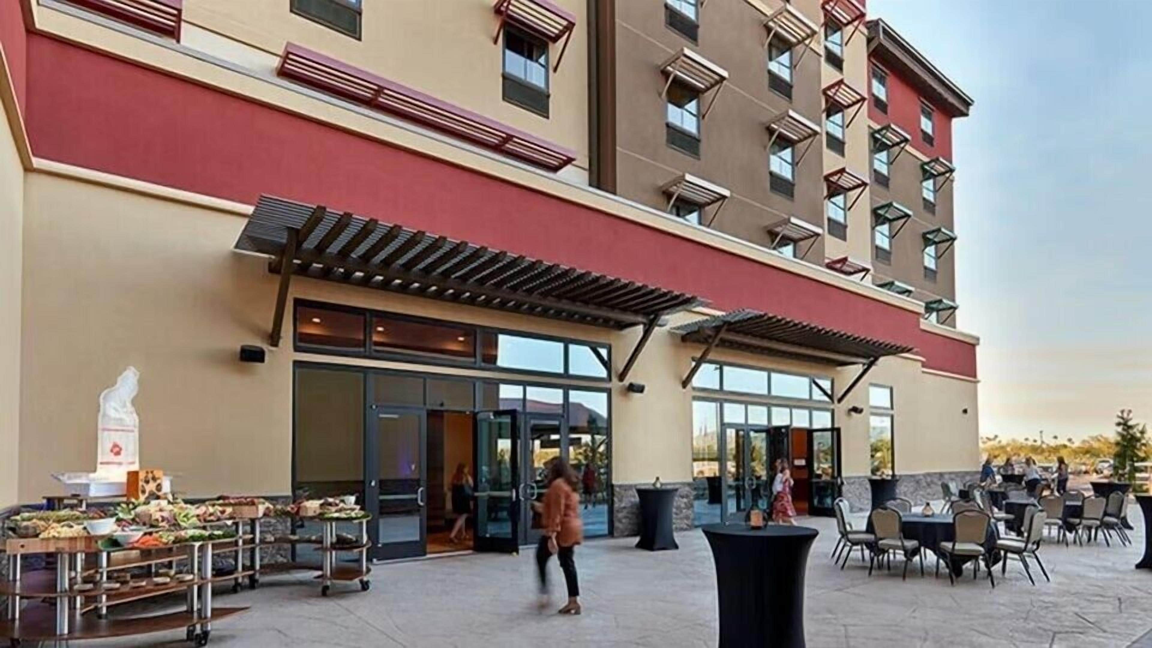 Een hotelgevel met een overdekt terras, een buffetopstelling en een entree.