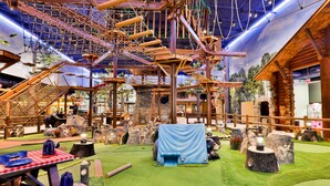 An indoor play area with a rope bridge, climbing structures, and a picnic table. - Great Wolf Lodge Arizona (Scottsdale)