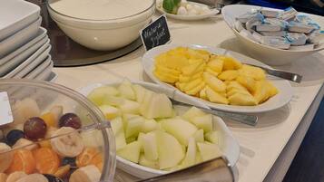 A buffet with various fruits, yogurt, and other food items.
