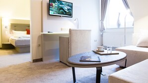 Una habitación de hotel con cama, escritorio, televisor, mesa y ventana.