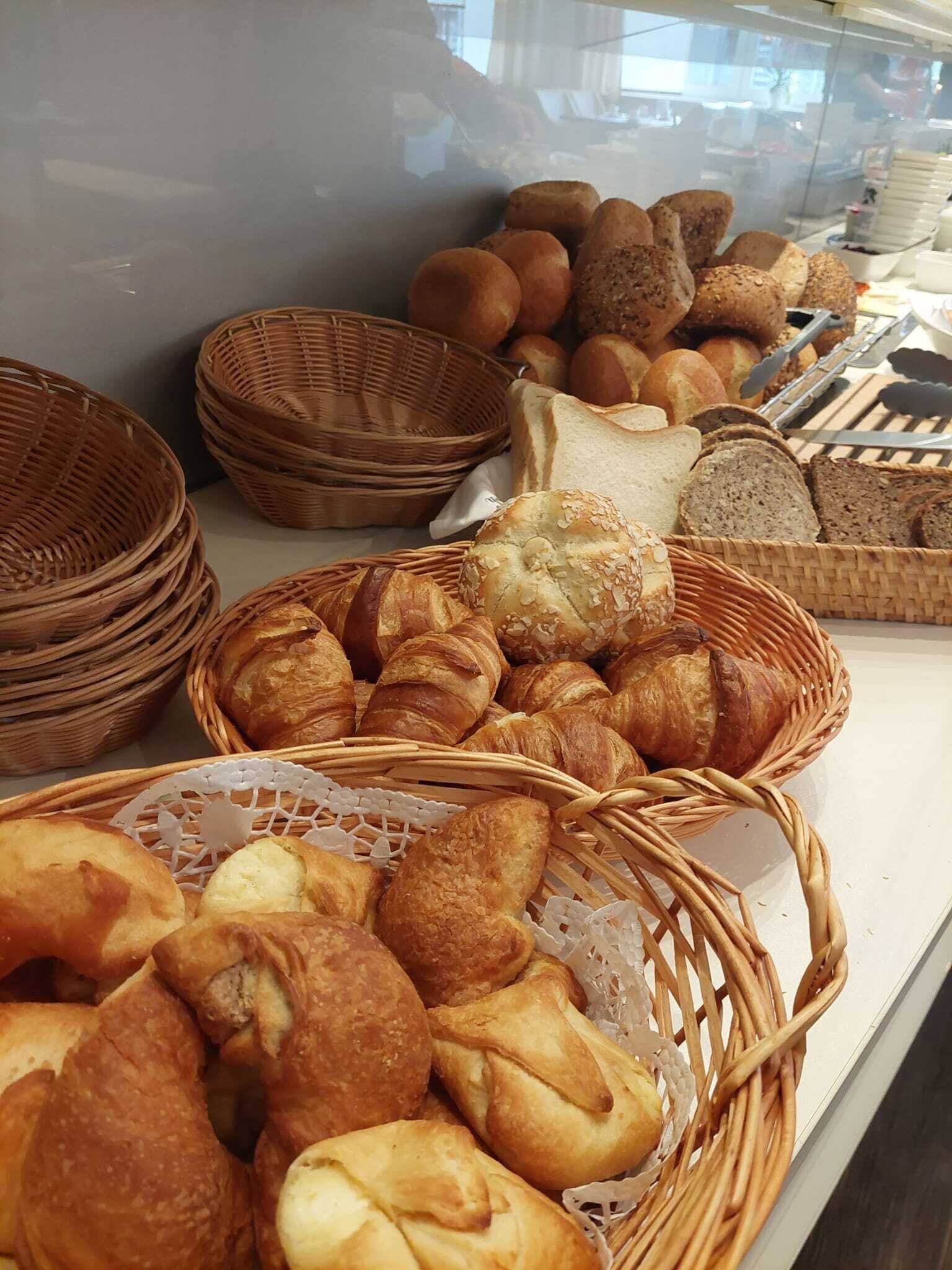 A display of various breads and pastries in wicker baskets.
