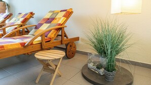 Una habitación con sillones de madera, una pequeña mesa de madera y una planta en maceta.