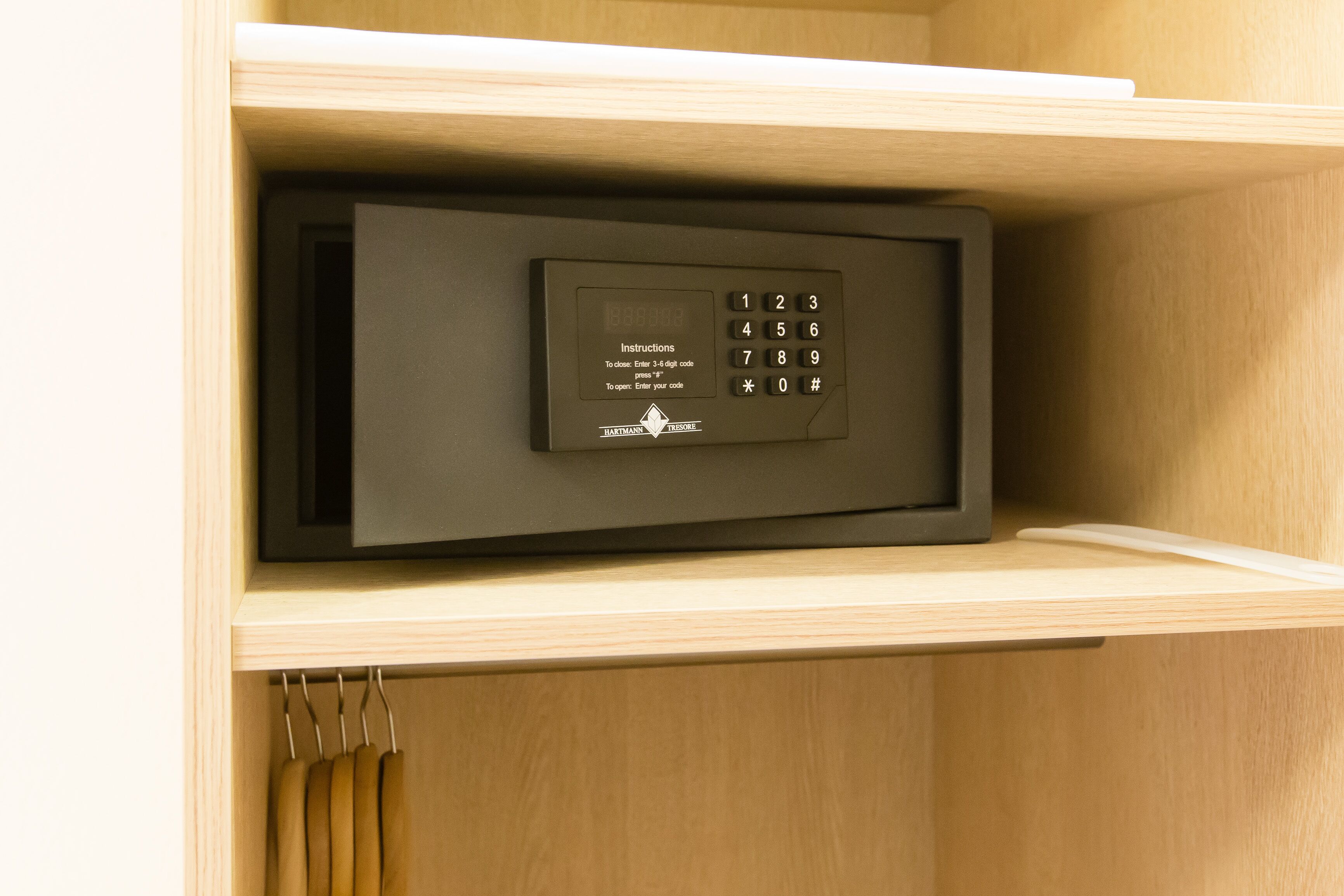 A secure safe with a keypad, placed in a wooden cabinet.