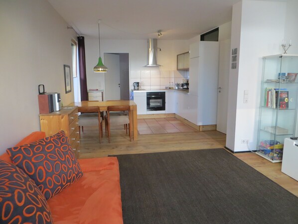 Un espacio habitable compacto con comedor, kitchenette y estantería.