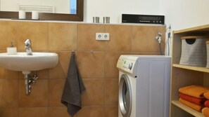Ein Badezimmer mit Waschbecken, Waschmaschine und Handtuchhalter.