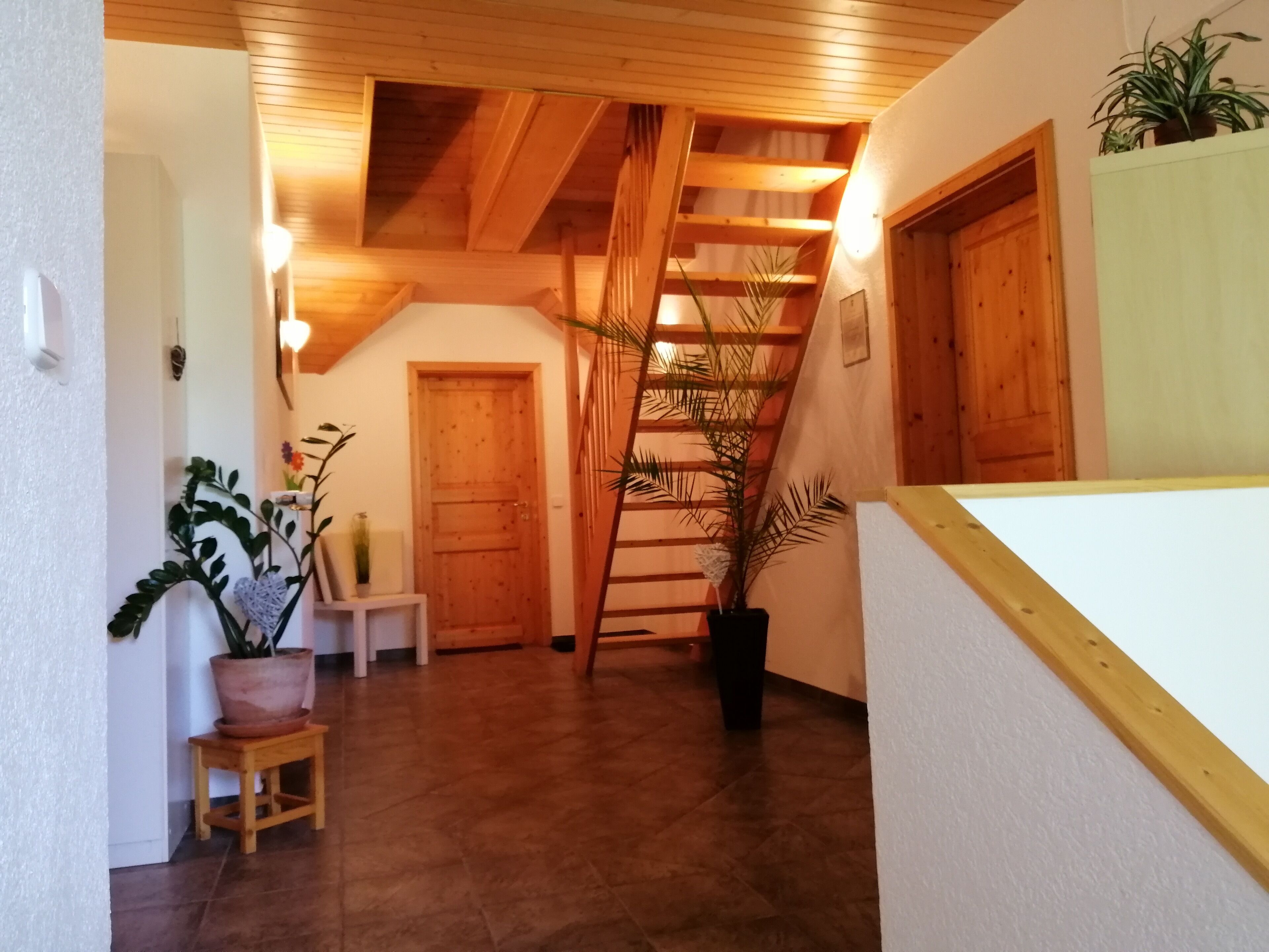 A wooden staircase leading to a loft bedroom with a sloped ceiling.