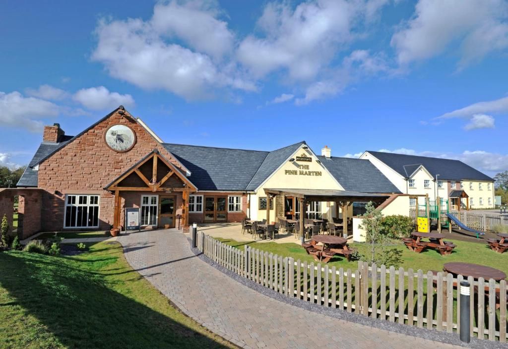 A building with a clock, a sign reading 'The Pine Marten,' and outdoor seating areas.