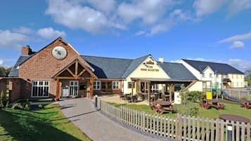 A building with a clock, a sign reading 'The Pine Marten,' and outdoor seating areas.