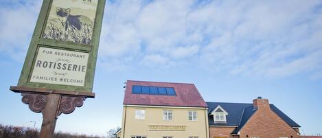 A pub named "The Pine Marten" with a signboard and a building with a red roof.