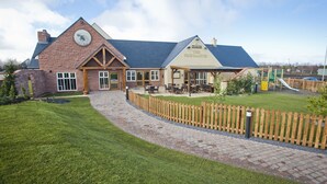 A building with a brick facade, a covered patio area, and a playground. - Pine Marten, Dunbar by Marston's Inns (Dunbar)