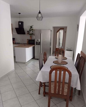 Une cuisine moderne dotée d’un îlot central, d’une table à manger avec des chaises et d’un luminaire suspendu.