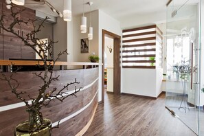 A reception area with a wooden reception desk, a glass partition, and a plant in a vase.