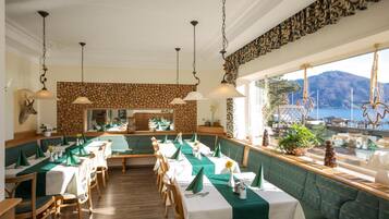 Ein Restaurant mit Meerblick, Holzböden und Tischdecken in Grün und Weiß.