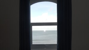 Una habitación con un ventanal grande que da a un mar tranquilo y un cielo nublado.