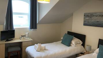 A hotel room with two beds, a desk with a computer, a lamp, and a painting on the wall.
