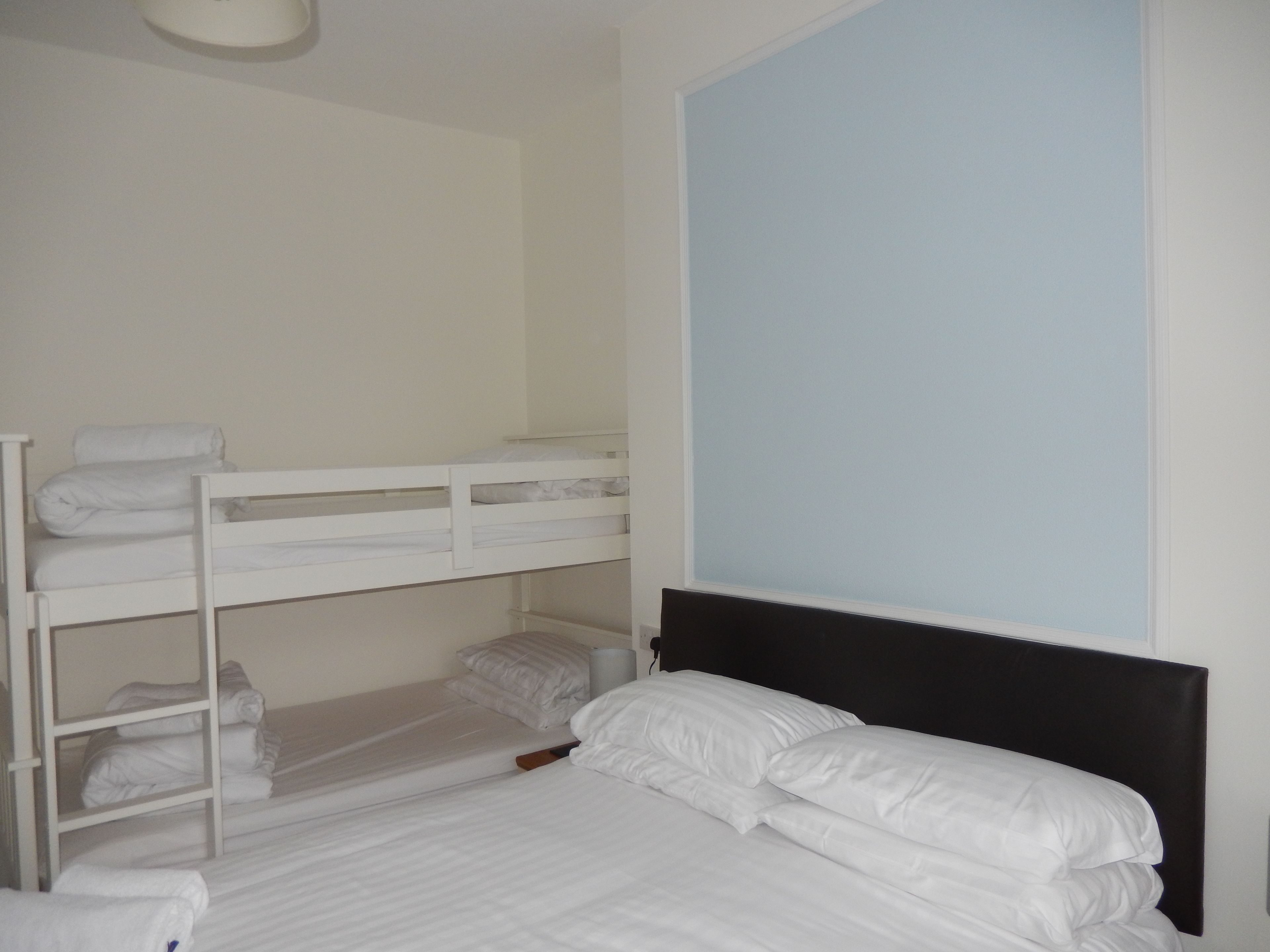 A bunk bed room with white bedding and a black headboard.