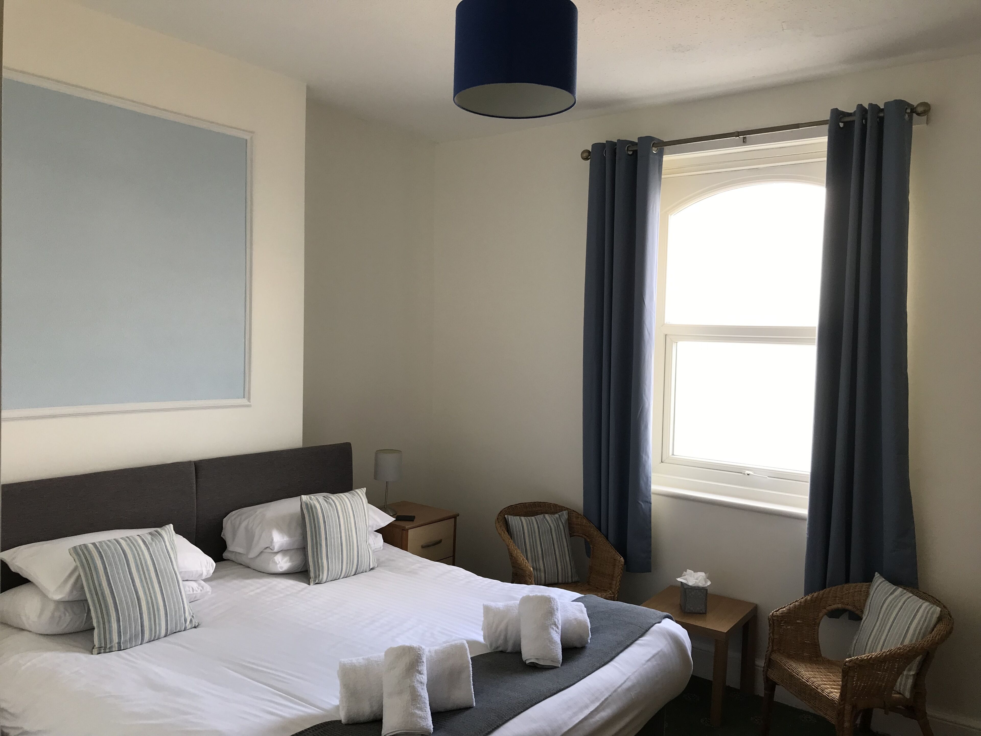 A neatly arranged hotel room with a large bed, two chairs, a small table, and a window with curtains.