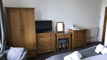 A hotel room with a bed, a desk with a computer, a wardrobe, and a chair.