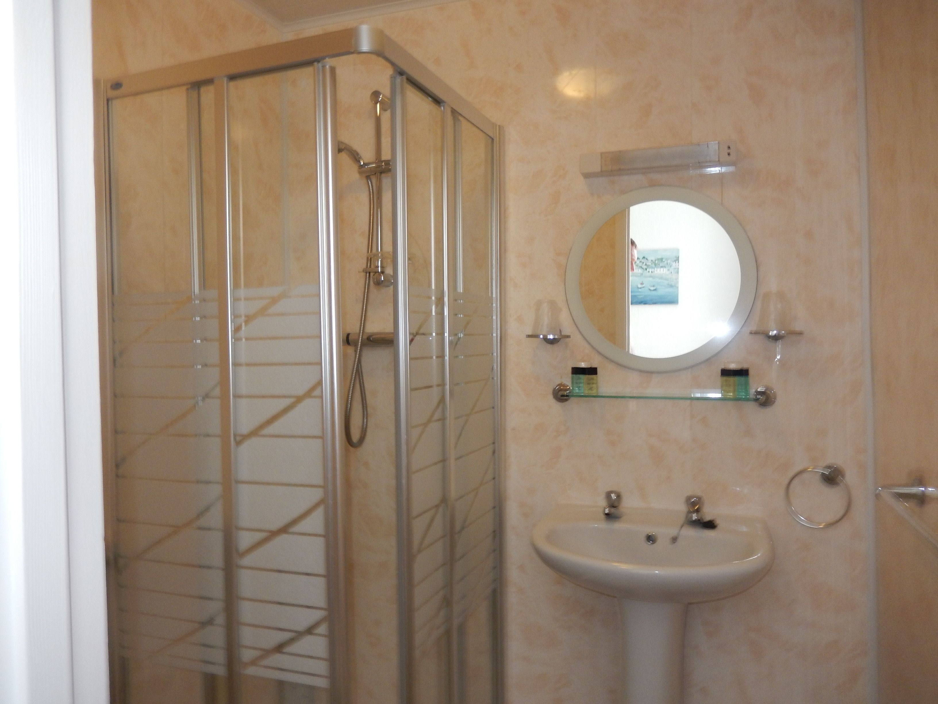 Un baño con cabina de ducha de vidrio, lavabo y espejo.