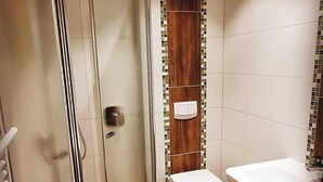 A bathroom with a glass shower enclosure, a toilet, and a sink.