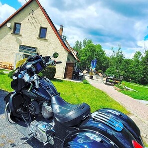 A motorcycle parked in front of a building with a sign that reads 'Esterblitz Hotel & Restaurant.'